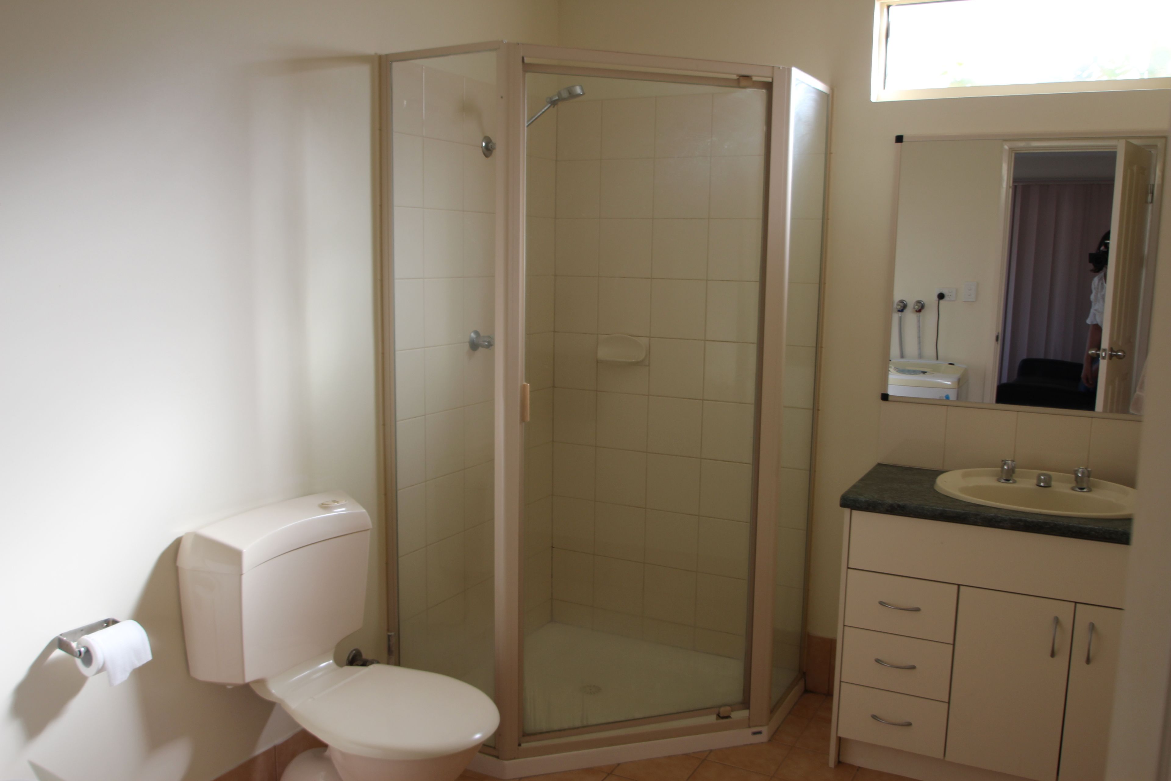 A bathroom with a toilet, a glass-enclosed shower, a sink, and a mirror.
