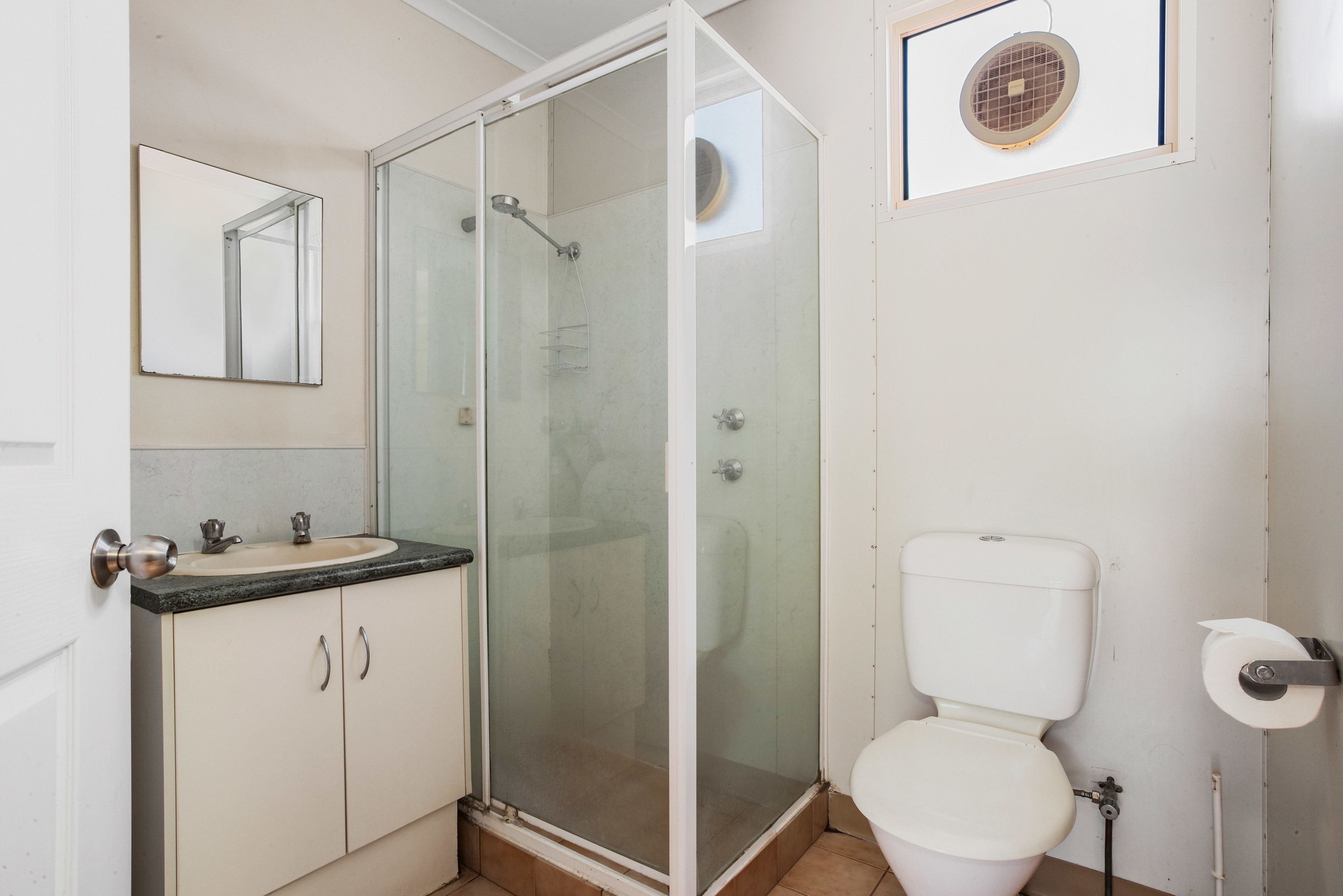Un baño con ducha de vidrio, lavamanos con espejo y retrete.