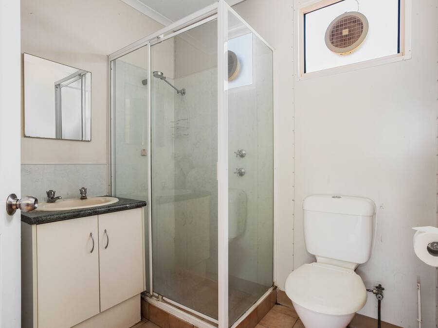 Un baño con ducha de vidrio, lavamanos con espejo y retrete.
