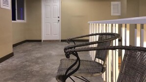 A hallway with a white door, a small window, and a wicker chair. - AN Apartment (Pattaya)