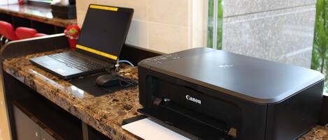 A reception desk with a laptop, a Canon printer, and a mouse.