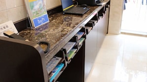 A reception desk with a laptop, a phone, and a sign with Japanese text. - Toyoko Inn Tsushima Izuhara (Tsushima)