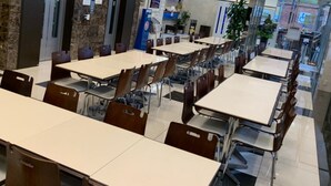 A cafeteria with multiple tables and chairs, marble walls, and a tiled floor. - Toyoko Inn Tsushima Izuhara (Tsushima)