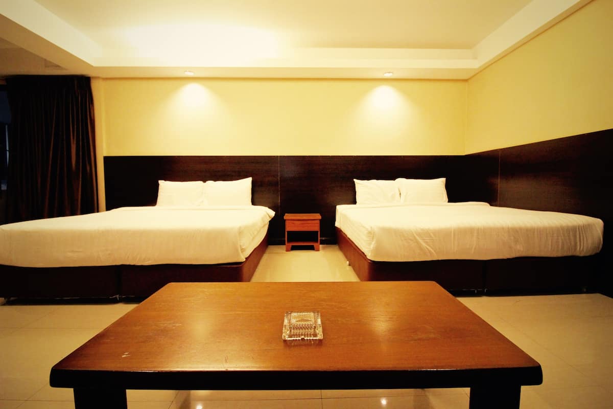 Une chambre d’hôtel avec deux lits, une table en bois et une petite table de chevet.