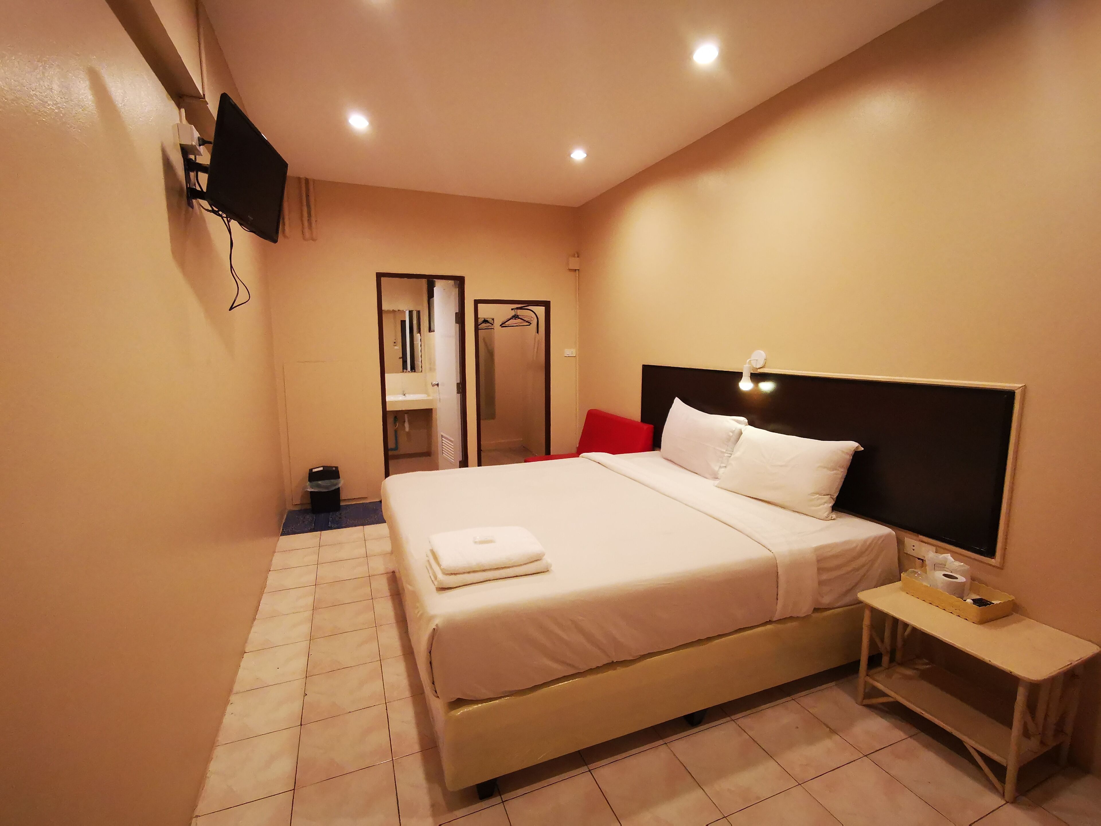 A hotel room with a bed, bedside table, and a TV mounted on the wall.