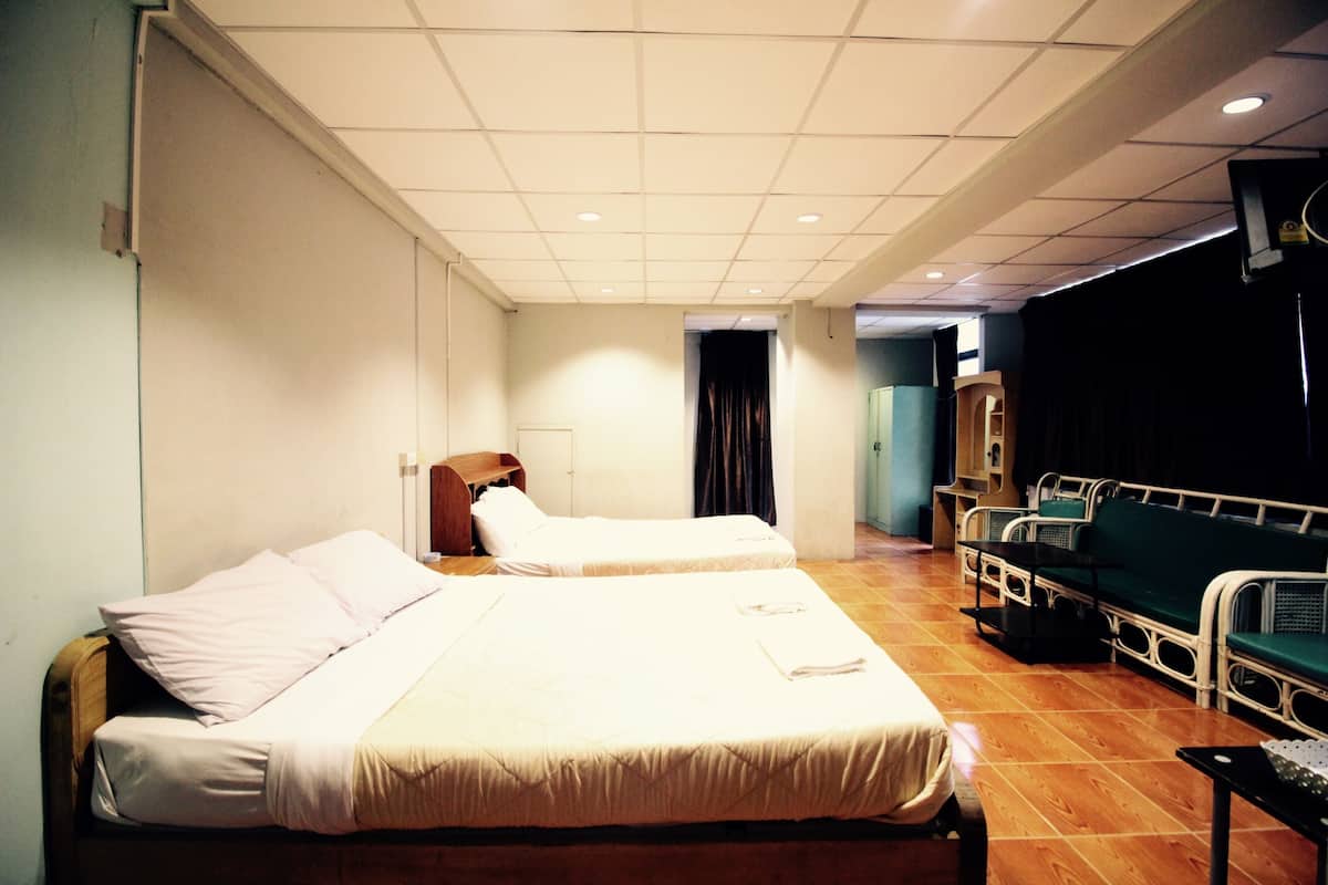 Une chambre d’hôtel avec deux lits, une petite table, un téléviseur et un coin salon agrémenté d’un rideau en fond.