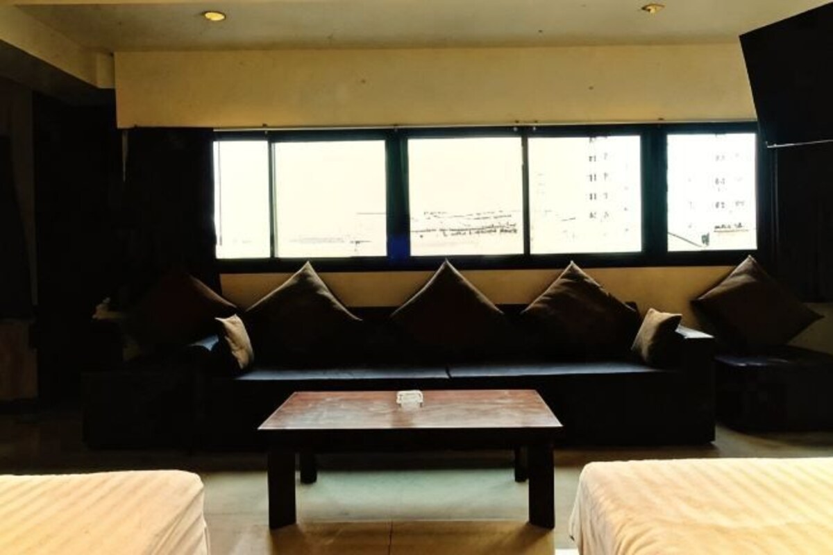 A room with a sofa, a coffee table, and a bed.