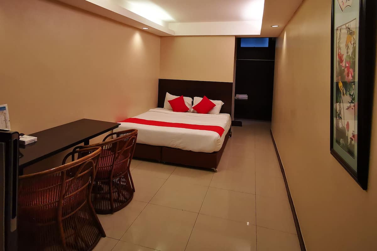 Une chambre d’hôtel avec un lit, un bureau et deux chaises.