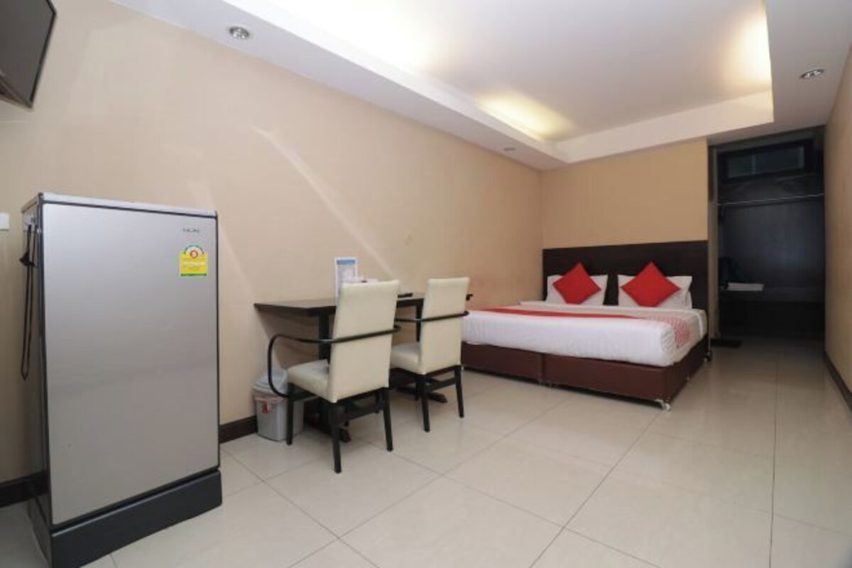 A hotel room with a bed, a desk, and a refrigerator.