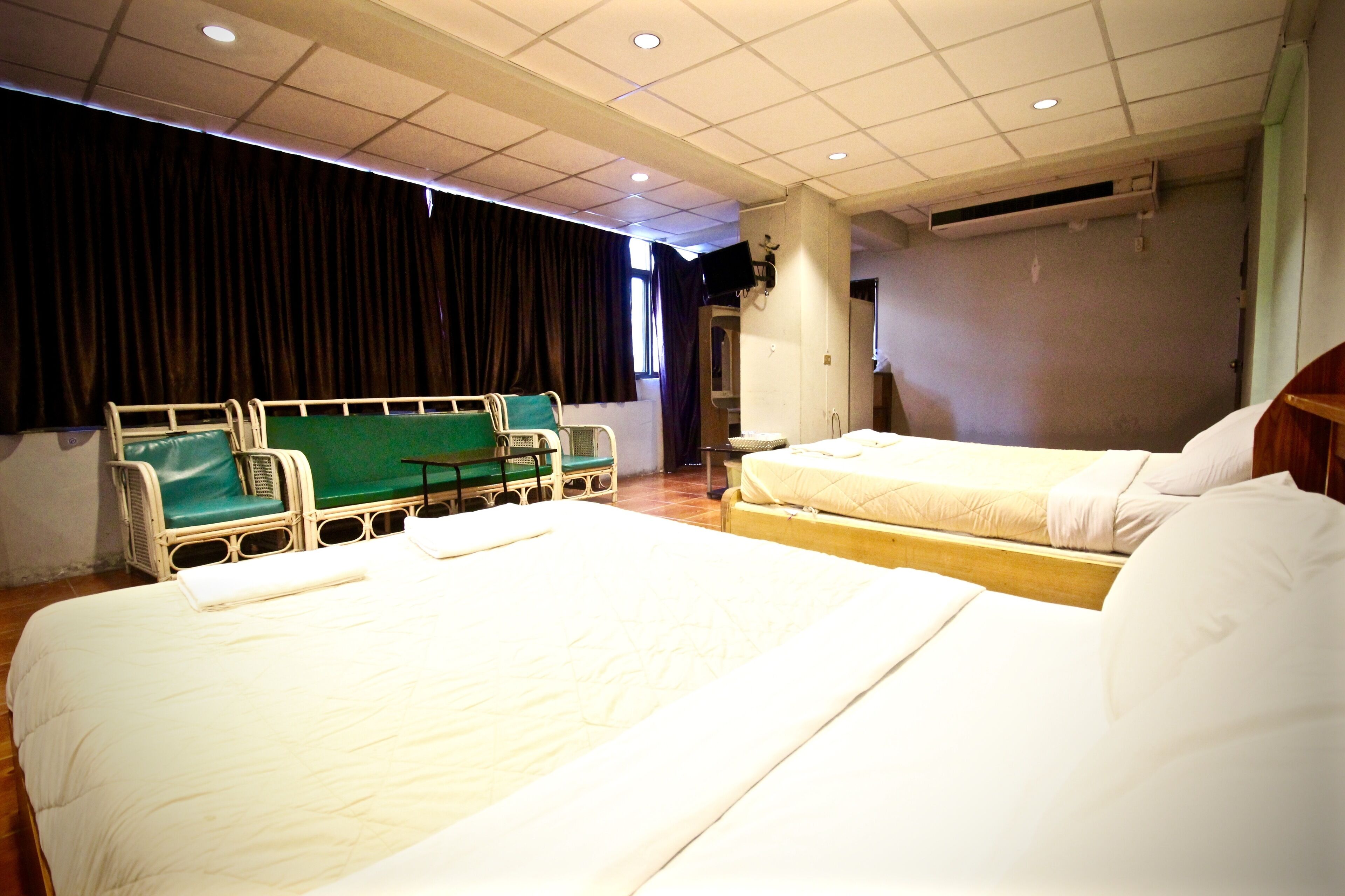 A hospital room with two beds, a green chair, and a television on the wall.