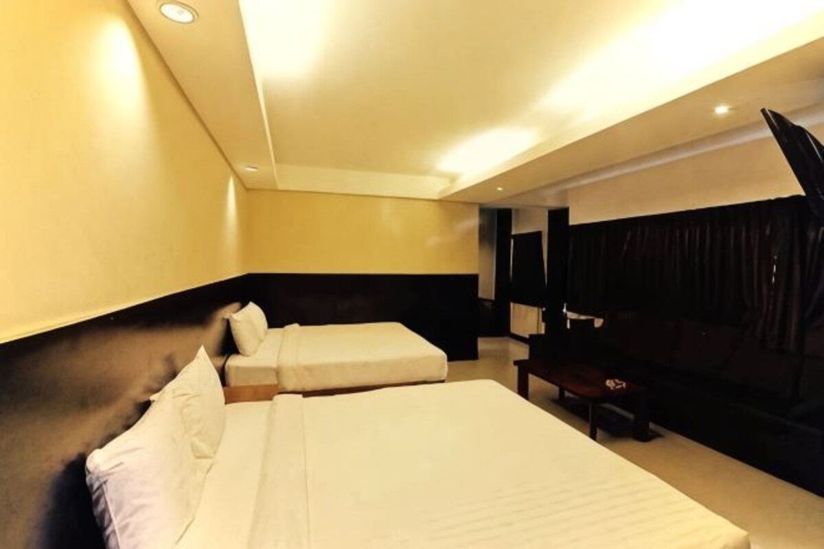 A hotel room with two beds, a desk, and a large window.