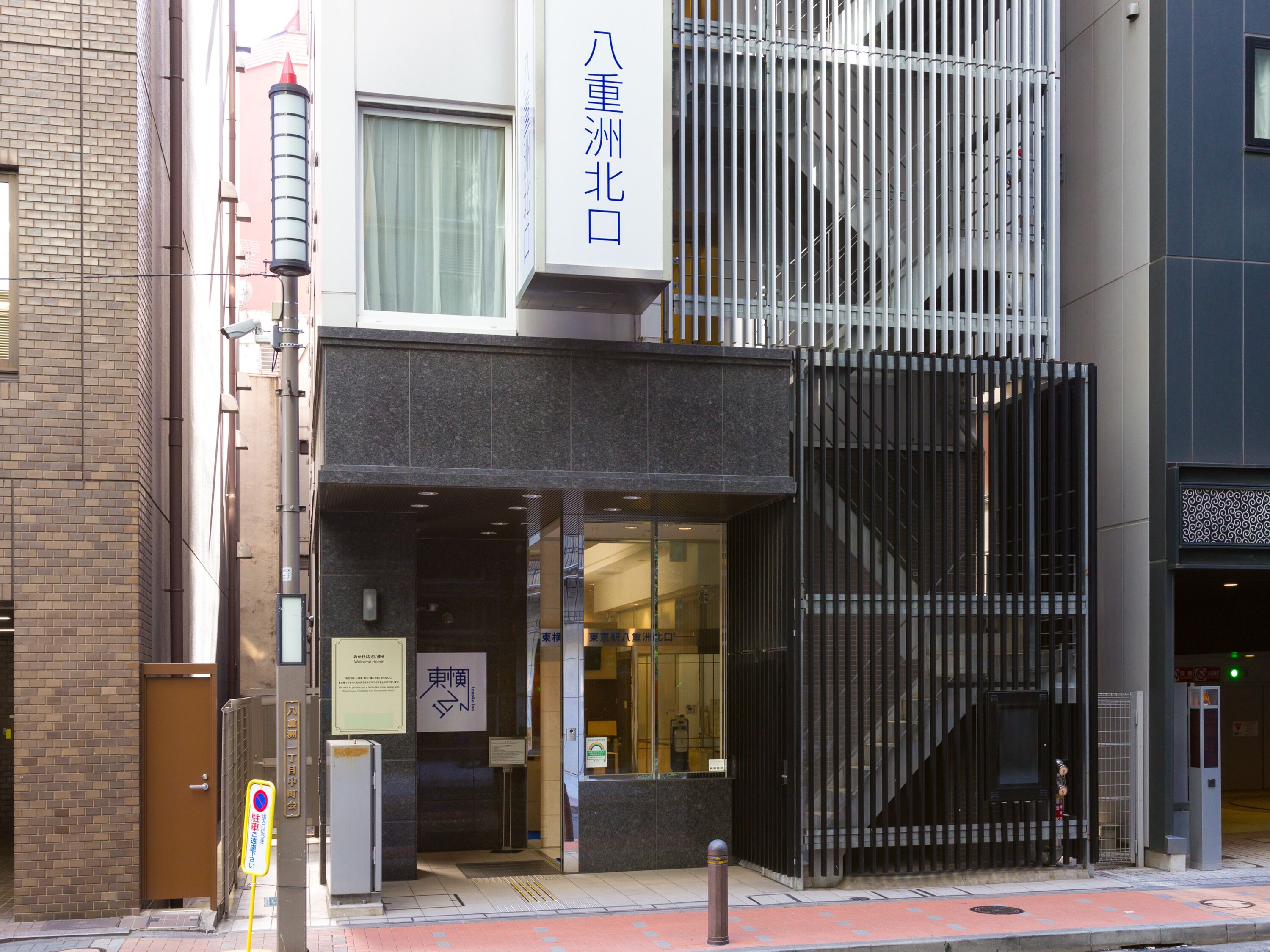A modern building with a glass entrance, a metal gate, and a sign with Japanese characters.