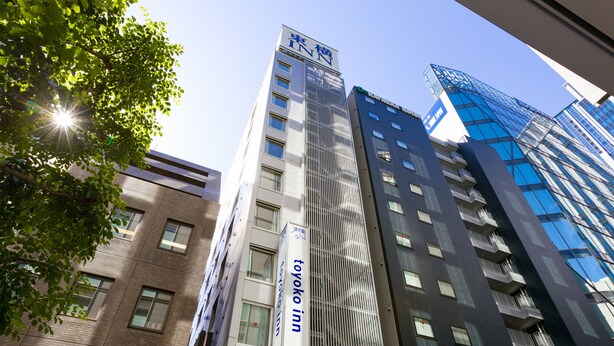 Un edificio moderno con un cartel llamativo de 'Toyoko Inn' y una vista despejada del cielo.