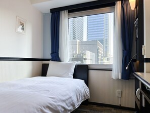 Une chambre d’hôtel avec un lit, une fenêtre avec des rideaux, un bureau et une vue sur de hauts immeubles.