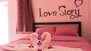 Un dormitorio con temática rosa, con cama, un letrero decorativo y una cortina.