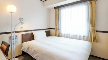 A hotel room with a neatly made bed, a bedside lamp, a clock on the wall, and a window with curtains.