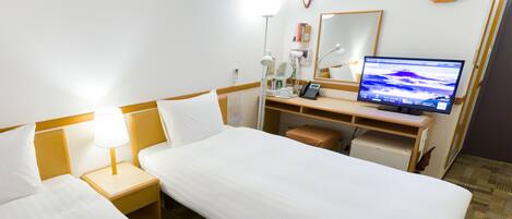 A hotel room with two single beds, a desk with a computer, a clock, and a mirror.