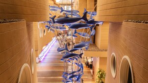 A corridor with blue whale sculptures, a tiled floor, and a staircase.