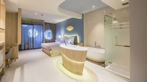 A modern hotel room with a large bathtub, a separate shower area, and a cozy bed with a view of the city.