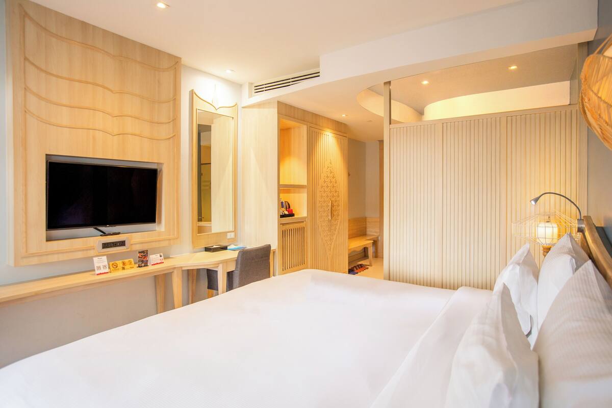 Una habitación de hotel con una cama grande, televisión, escritorio y baño.