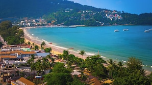 A coastal town with a beach, boats, and buildings on a hillside.