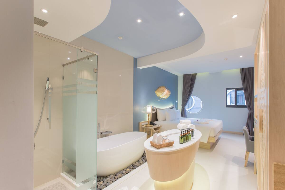 Un baño moderno con ducha de vidrio, bañera independiente y tocador con artículos de aseo.