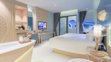 Une chambre d’hôtel moderne équipée d’un grand lit, d’un bureau, d’une télévision et d’une baignoire.