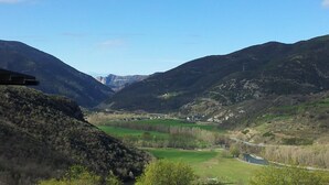 A mountainous landscape with a river, fields, and a few buildings. - Mountain apartment (SORT)