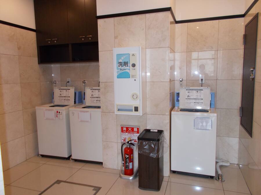 Un baño de hotel con lavamanos, espejo y extintor.