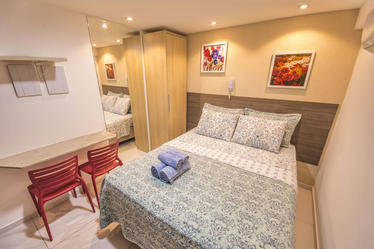 Un dormitorio con cama, escritorio y dos sillas.