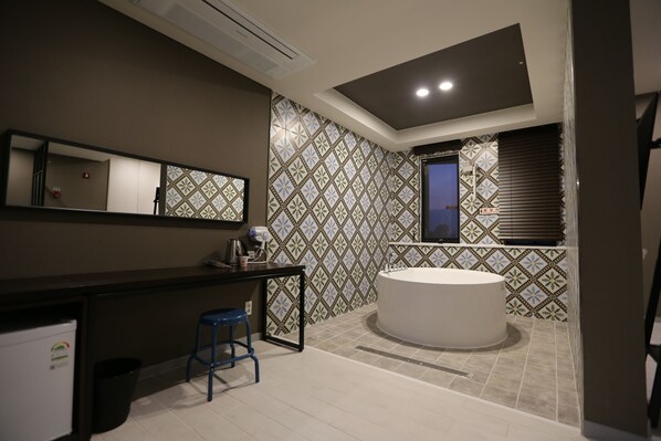 Une salle de bain moderne avec une grande baignoire, un meuble-lavabo avec un miroir et un tabouret bleu.