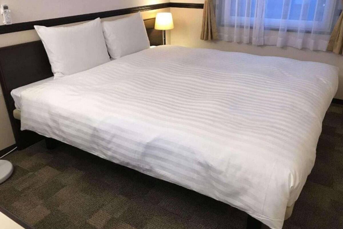 Une chambre d’hôtel avec un grand lit, une lampe de chevet et une fenêtre avec des rideaux.