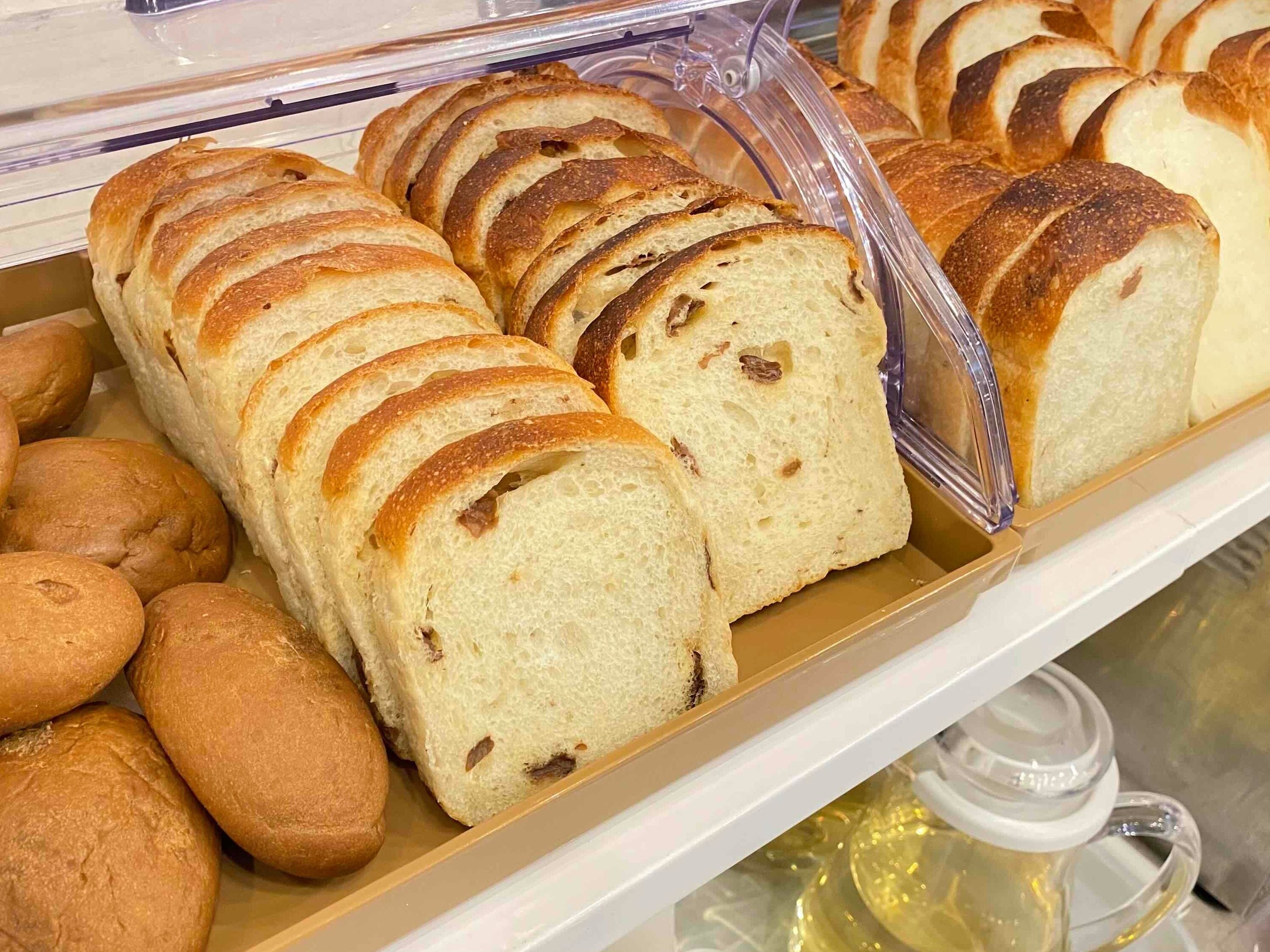 Una vitrina de panadería con pan de molde y bollos.