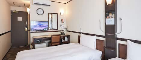 Una habitación de hotel con dos camas, un escritorio con computadora, televisor, reloj y espejo.