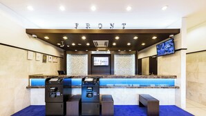 A hotel reception area with a marble counter, a digital screen, and a blue carpet. - Toyoko Inn Tsu-eki Nishi-guchi (Tsu)