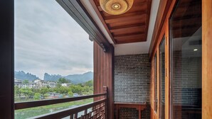 Un balcon donnant sur une rivière et des montagnes, avec des balustrades en bois et un luminaire décoratif au plafond.