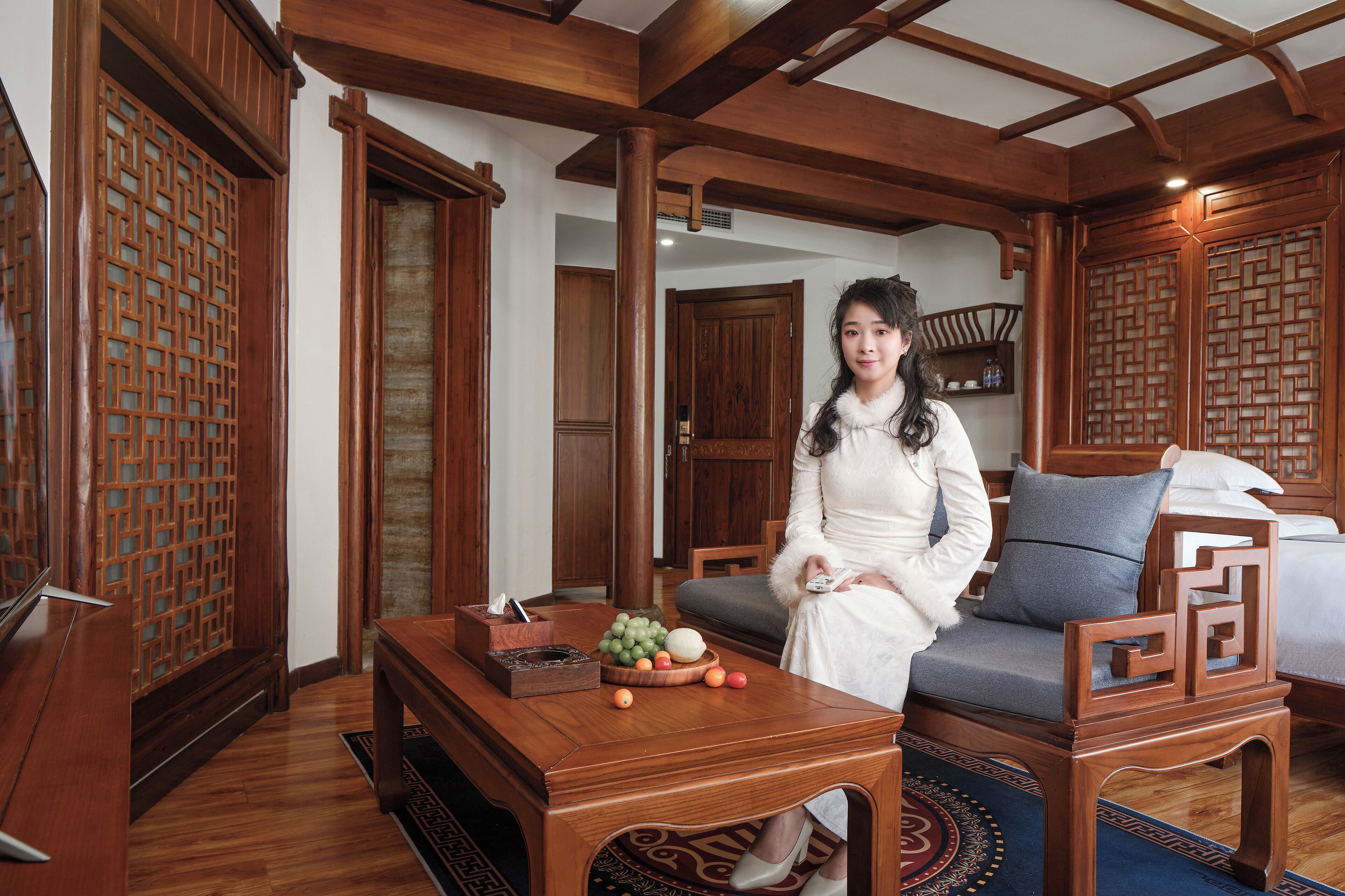 A traditional room with wooden furniture, a sofa, a table with fruit, and a decorative screen.