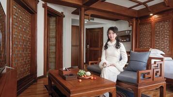 A traditional room with wooden furniture, a sofa, a table with fruit, and a decorative screen.