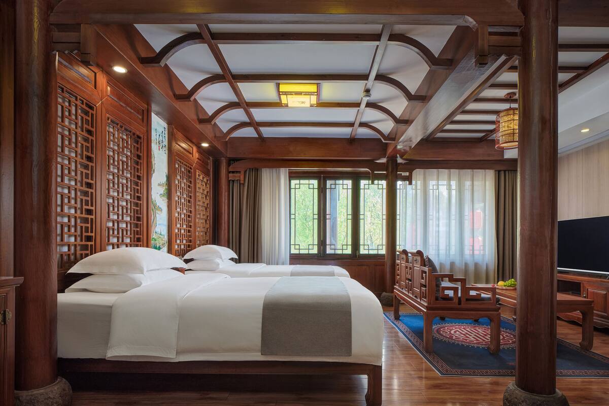Una habitación tradicional de madera con una cama grande, muebles de madera y vistas a la vegetación.