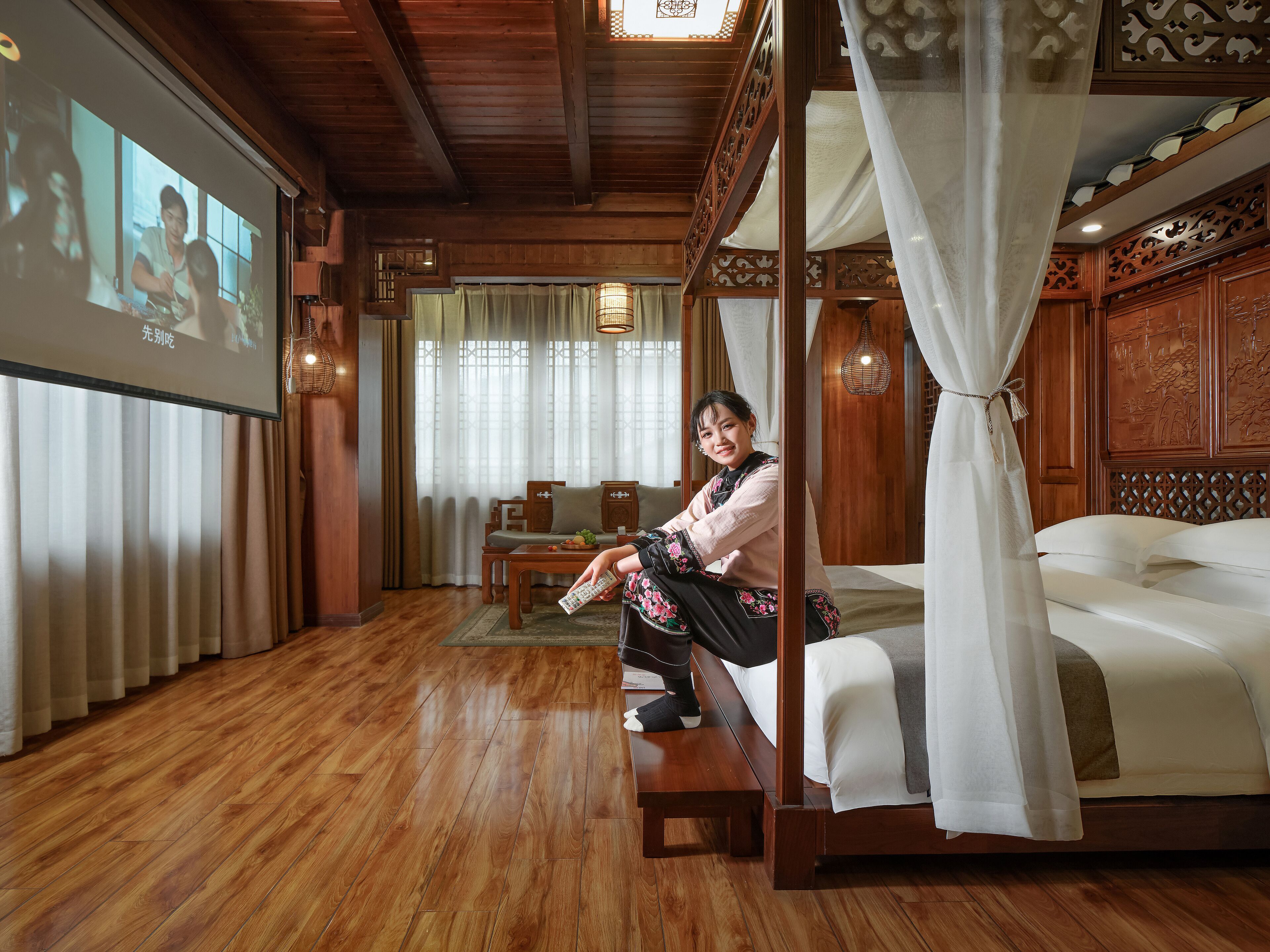 A traditional wooden room with a four-poster bed, a television screen, and a dining area.