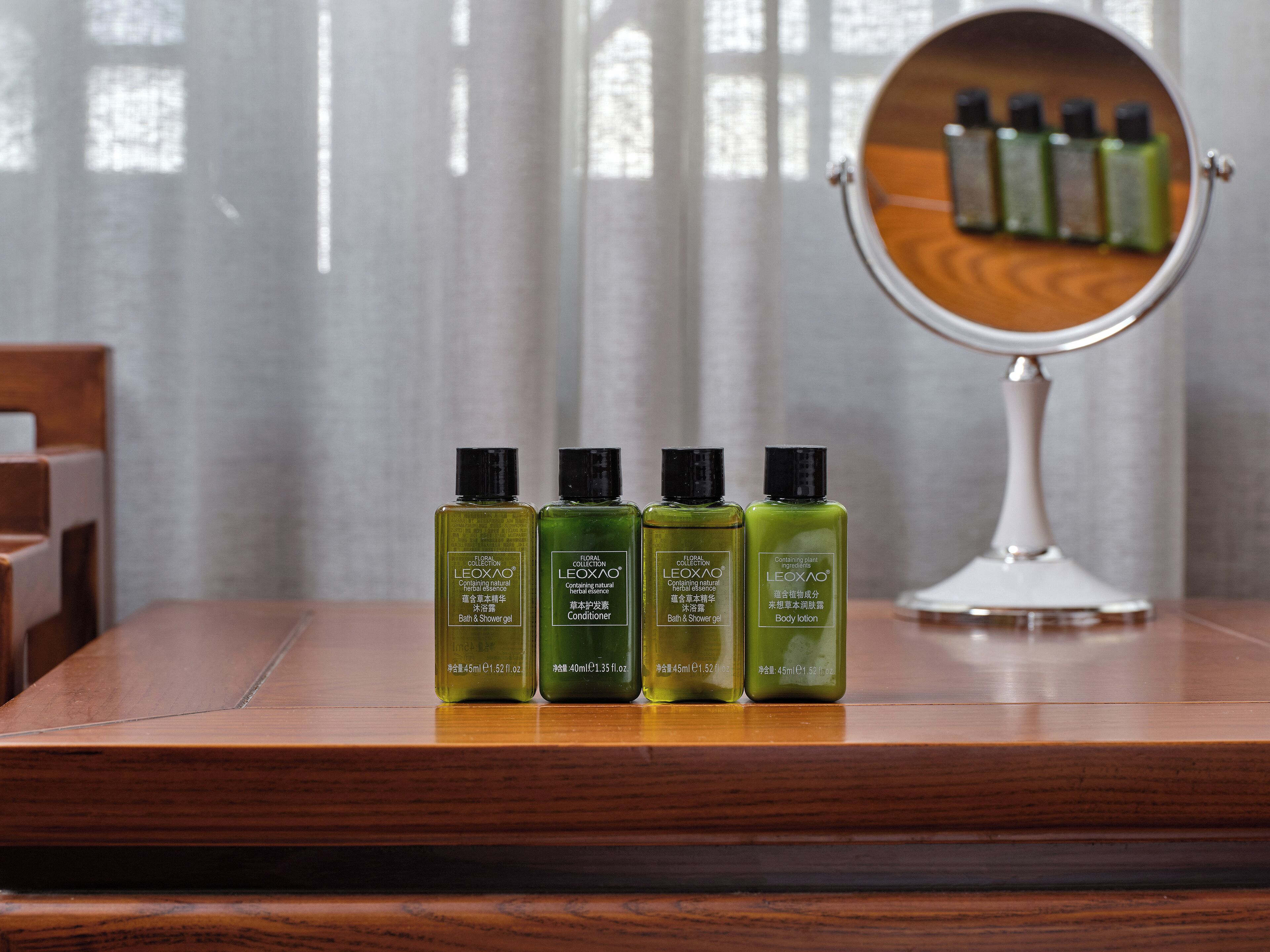 Una mesa de madera con tres botellas de gel de baño y ducha LEOXAO, una botella de acondicionador LEOXAO y una botella de loción corporal LEOXAO.