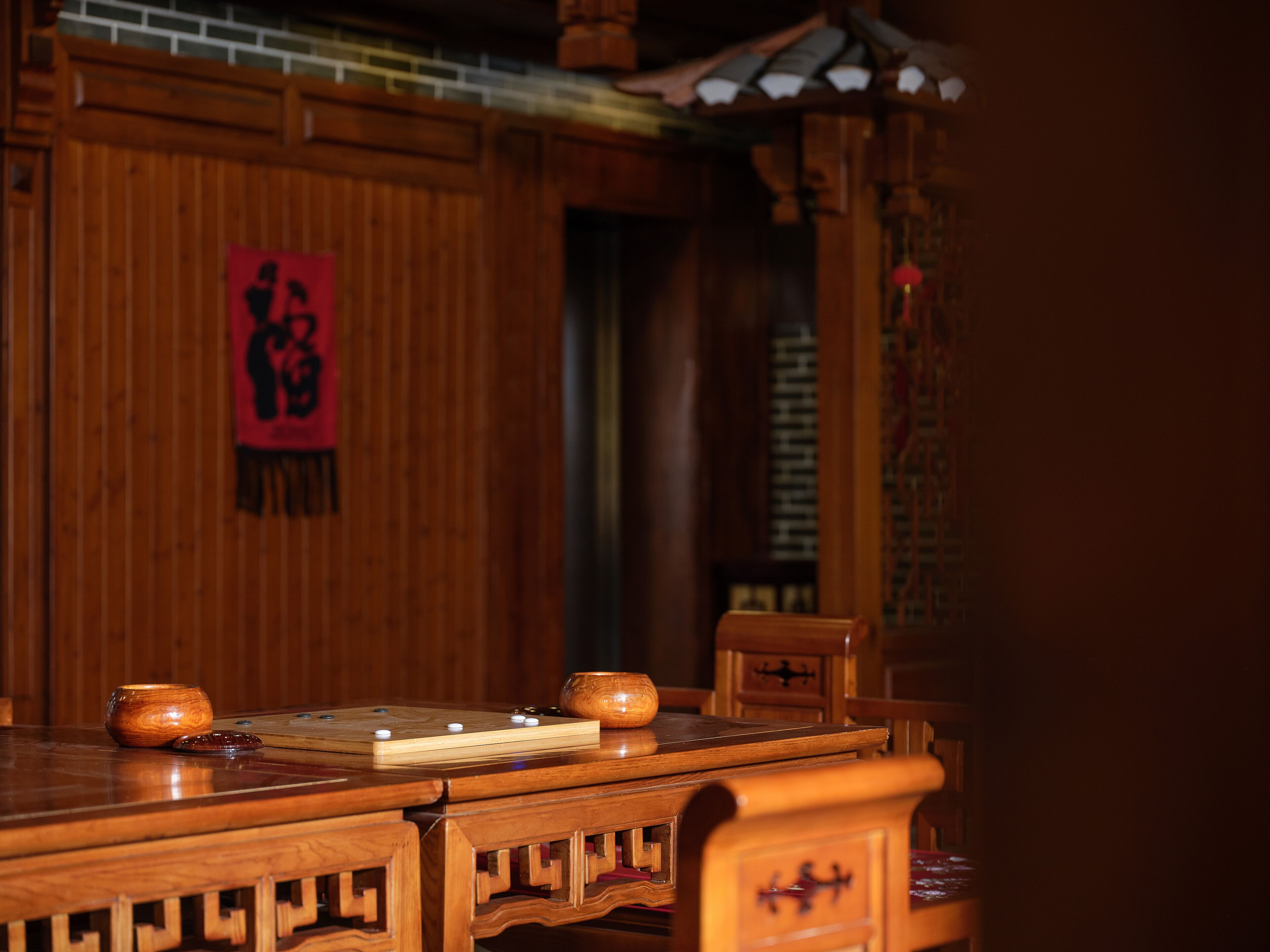 Una mesa de madera tradicional con un juego de ajedrez y un adorno colgante rojo.