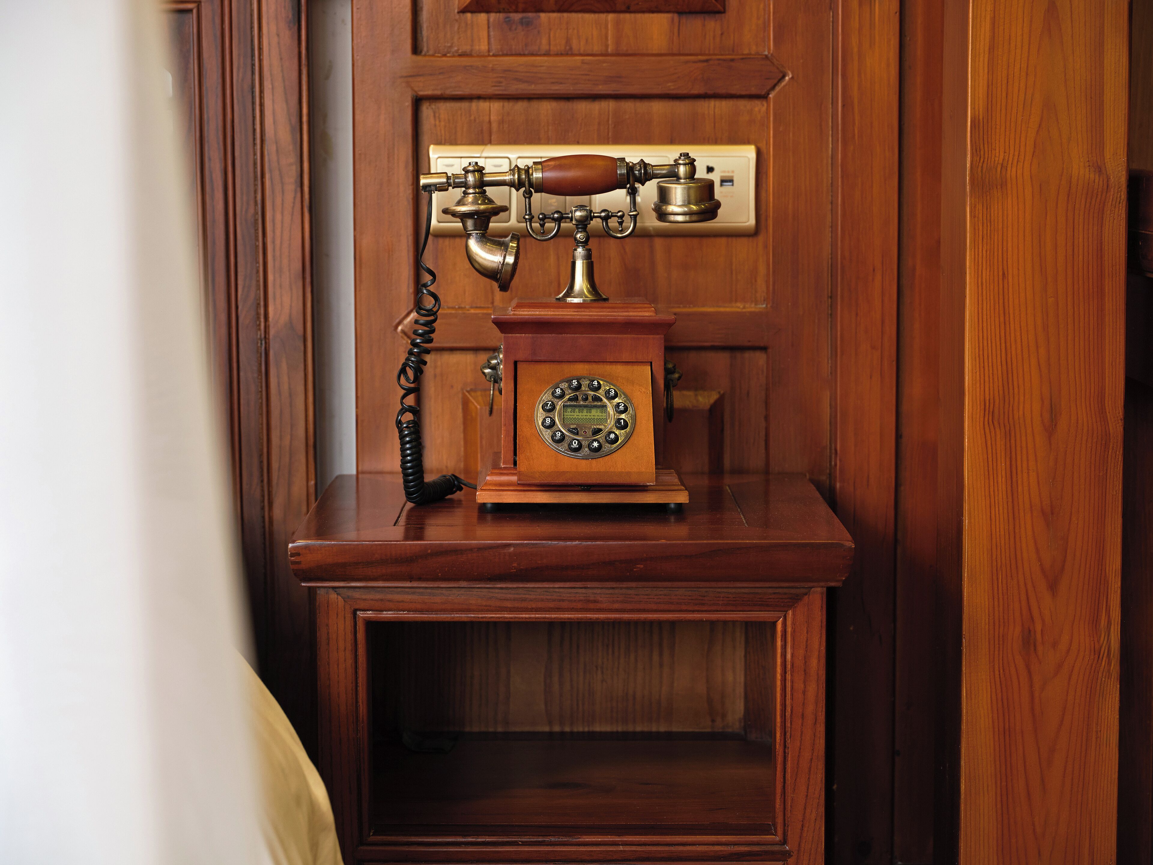 Eine hölzerne Telefonzelle mit Wähltisch und Kordondurchgangshörer.
