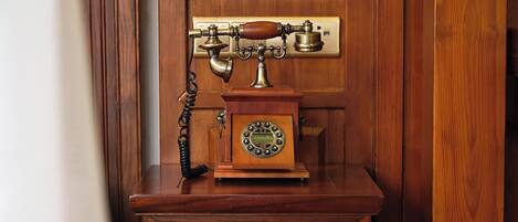A wooden telephone booth with a rotary dial and a corded handset.