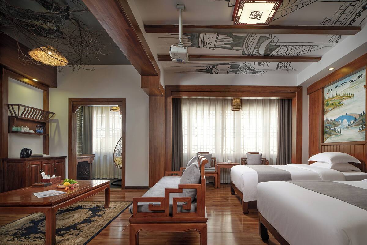 Una habitación de hotel con muebles de madera, una mesa de comedor, un sofá y una cama.