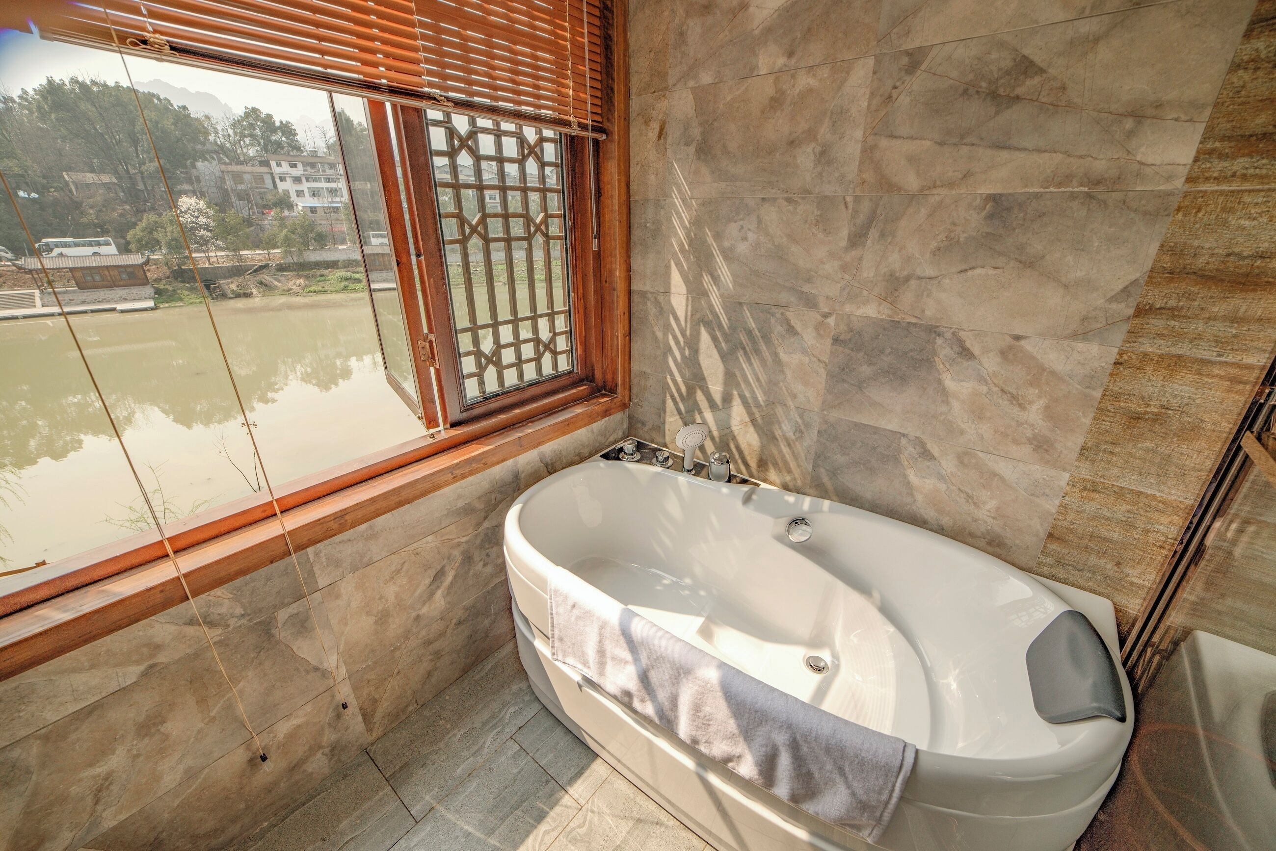 A bathroom with a bathtub, a window with a metal grille, and stone walls.