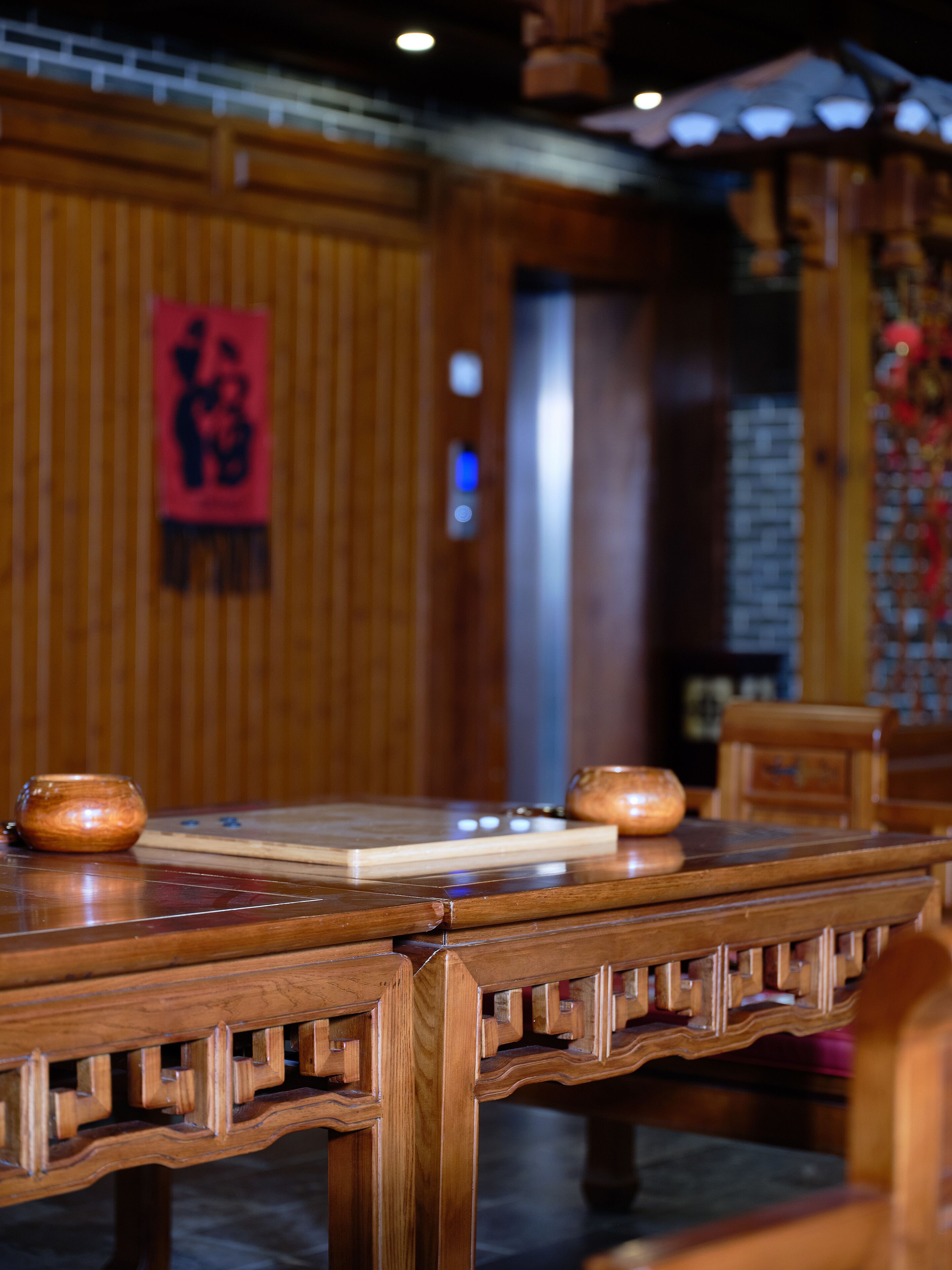Een traditionele houten tafel met een rood bord aan de muur.