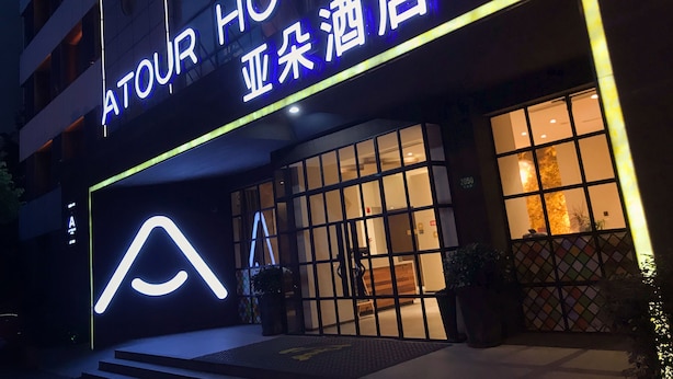En hotellentrén med en neonskylt, en modern fasad och ett tydligt synligt husnummer.