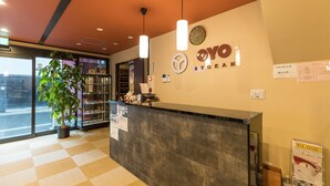 A reception area with a checkered floor, a reception desk, a potted plant, a clock, and a sign with the name "OYO". - Asakusa No Yado Hanaakari (Tokyo)