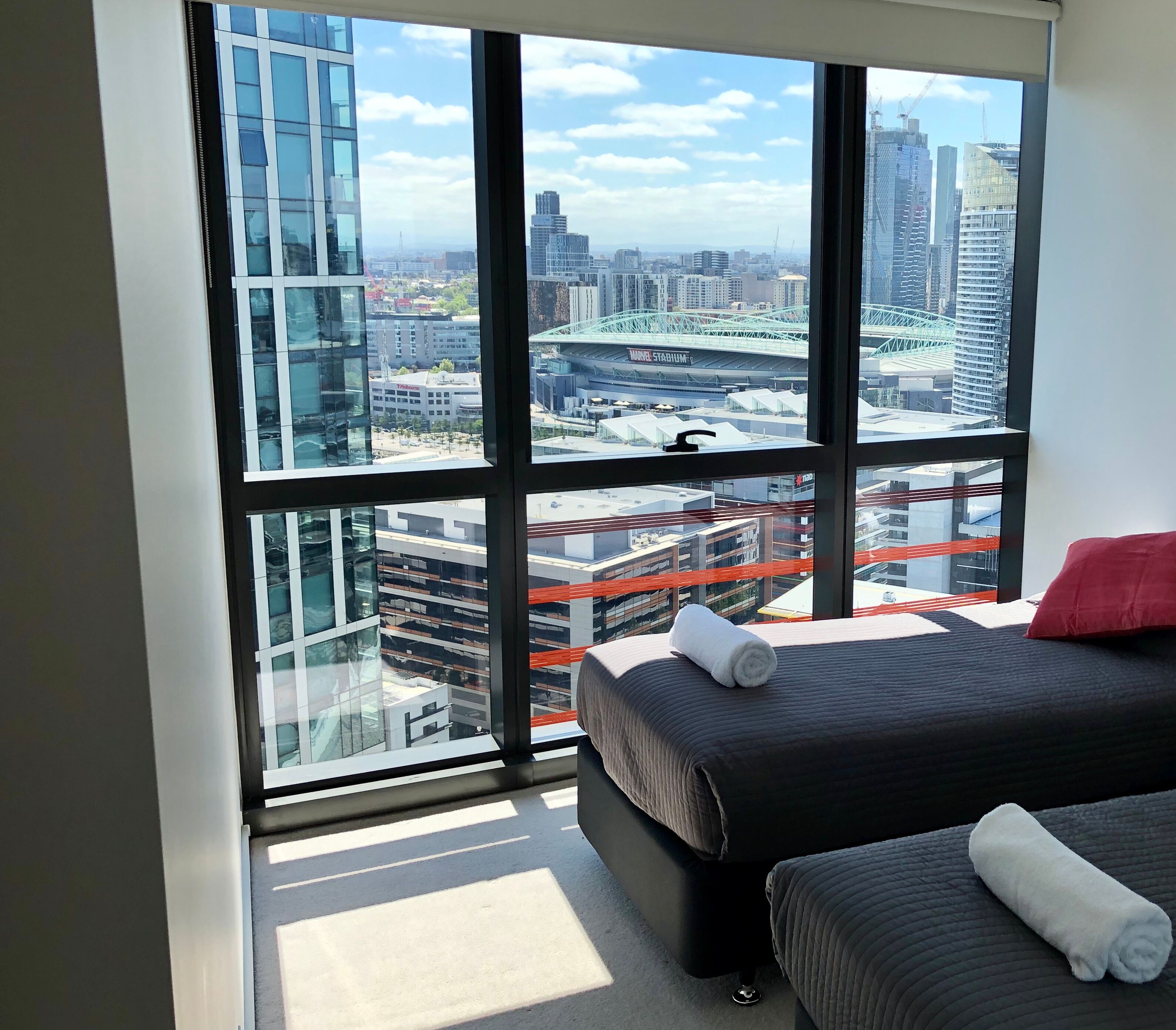 Ein modernes Hotelzimmer mit großen Fenstern und Blick auf die Stadt, einschließlich einer Brücke und einem Stadion.